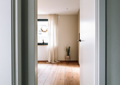 Offene weiße Innentür mit Blick auf einen Raum mit schönem Holzboden – Innenausbau von der Schreinerei Kappus aus Ettenheim