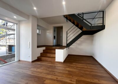 Holzboden mit Holztreppe und anschließender Wendeltreppe – im Hintergrund eine weiße Tür. Innenausbau von Schreinerei Kappus in Ettenheim